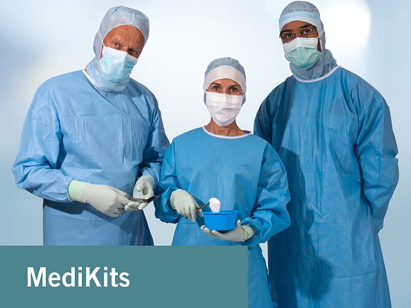 three persons dressed in operation gowns with surgical hoods ans caps wearing surgical gloves and face masks holding forceps