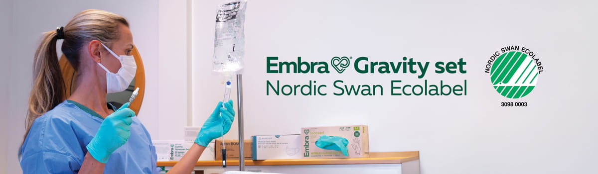 A healthcare worker sets up the Embra® Gravity Set for intravenous infusion, with the Nordic Swan Ecolabel logo visible, highlighting the product’s eco-friendly certification and safe medical use.